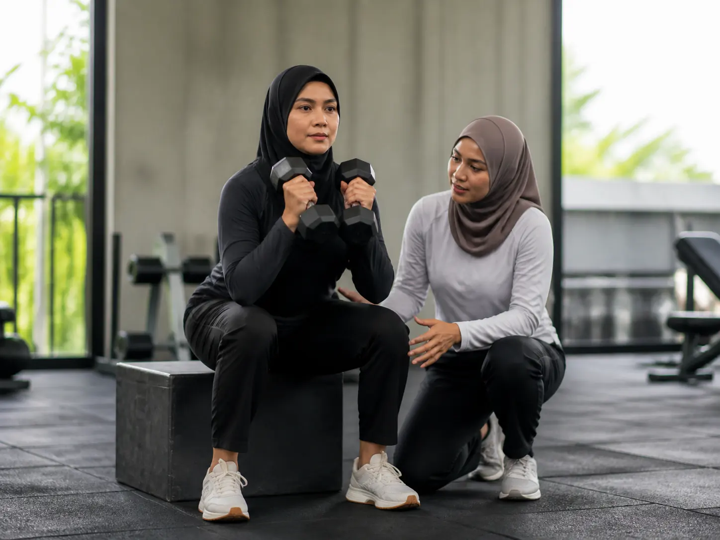 Seorang wanita melakukan squat kotak dumbbell dengan bimbingan